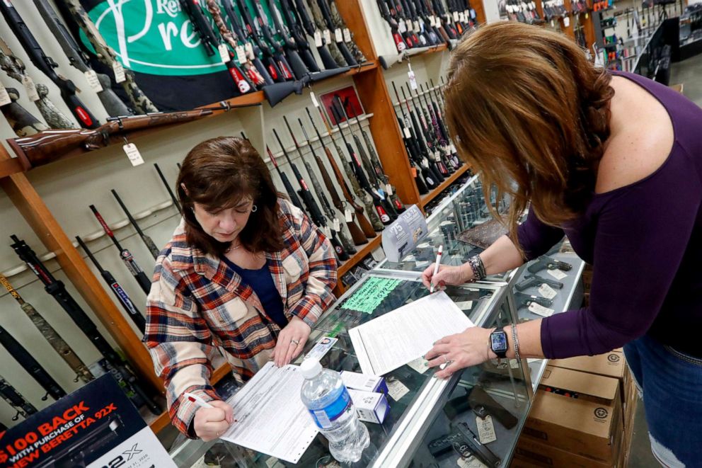 PHOTO: Andrea Schry, right, fills out the buyer part of legal forms to buy a handgun as shop worker Missy Morosky fills out the vendors parts after Dukes Sport Shop reopened, March 25, 2020, in New Castle, Pa.