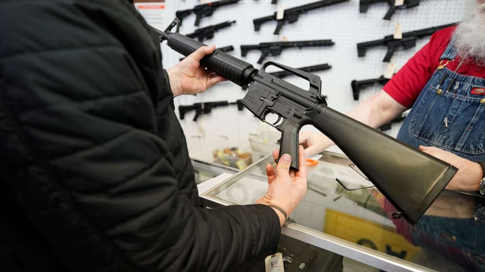 PHOTO: In this March 25, 2021, file photo, a salesperson shows an AR-15 rifle to a customer at a store in Orem, Utah.