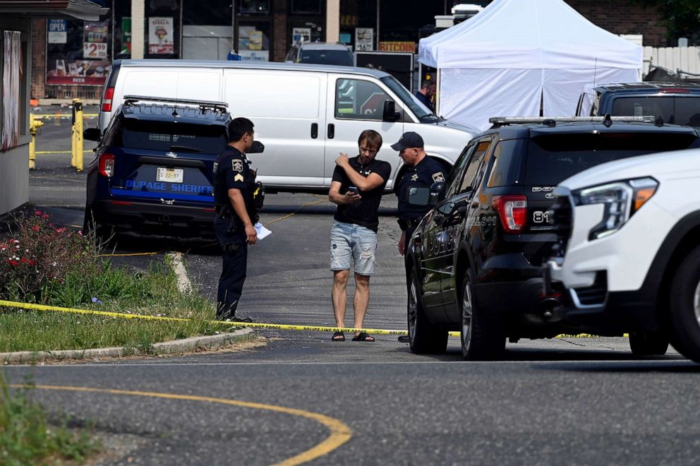 PHOTO: Investigators talk with a person at the scene of an overnight mass shooting at a strip mall in Willowbrook, Ill, June. 18, 2023.