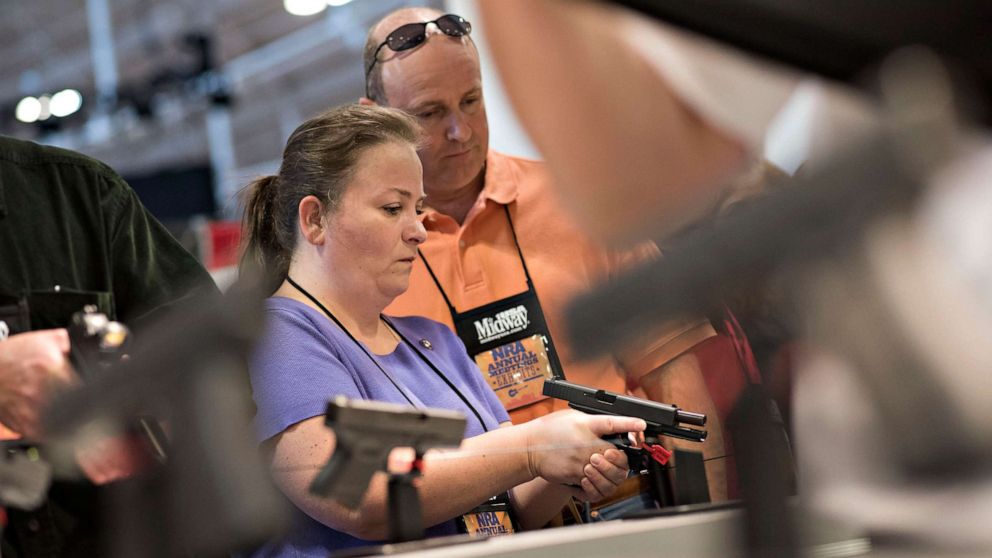 PHOTO: Atendees look at weapons on the exhibition floor of the 144th National Rifle Association (NRA) Annual Meetings and Exhibits in Nashville, Tenn, April 11, 2015.