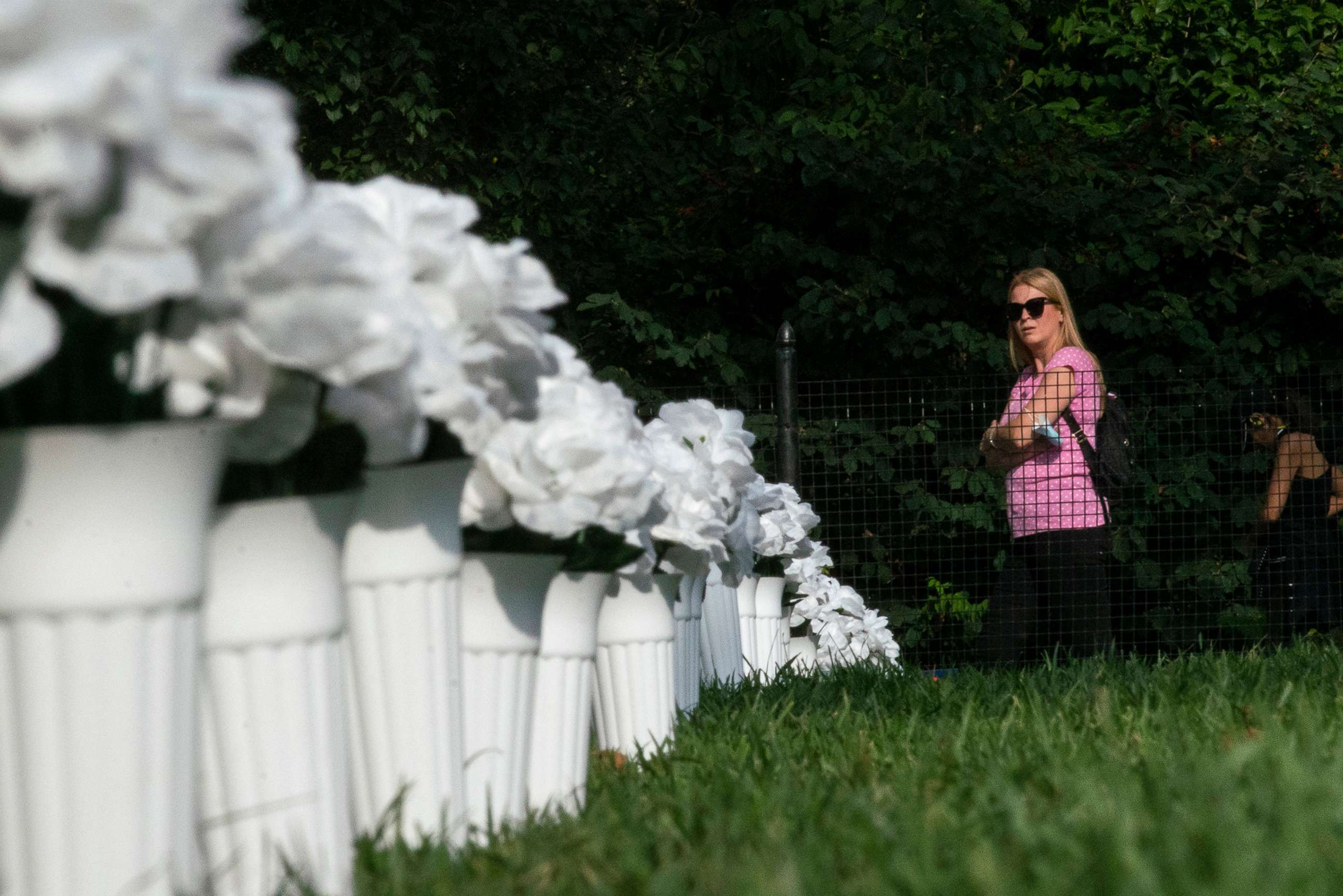 PHOTO: A woman looks at vases of white flowers that are part of an installation representing 1,050 lives lost by gun violence in New York last year, Oct. 7, 2021, in New York.