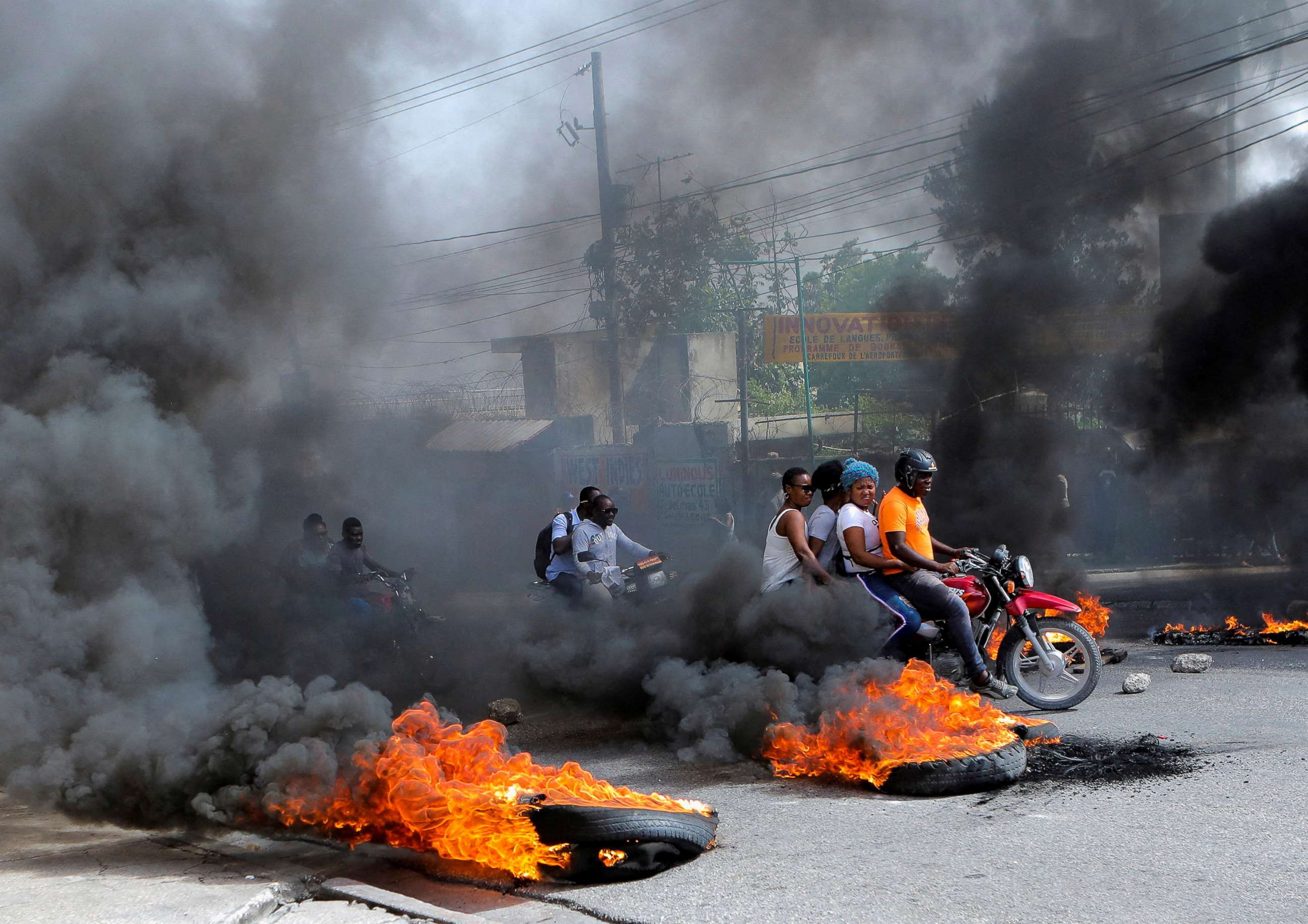 PHOTO: Motorcycle drivers pass through a burning road block as anger mounted over fuel shortages that have intensified as a result of gang violence, in Port-au-Prince, Haiti, July 13, 2022.
