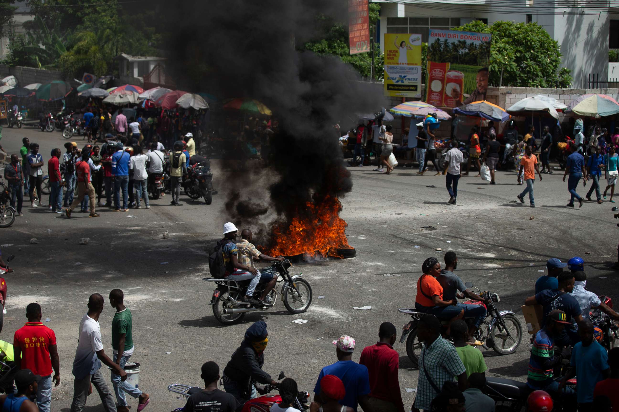 PHOTO: People walk around burning tires set up by taxi drivers to protest the country's fuel shortage in Port-au-Prince, Haiti, July 13, 2022.