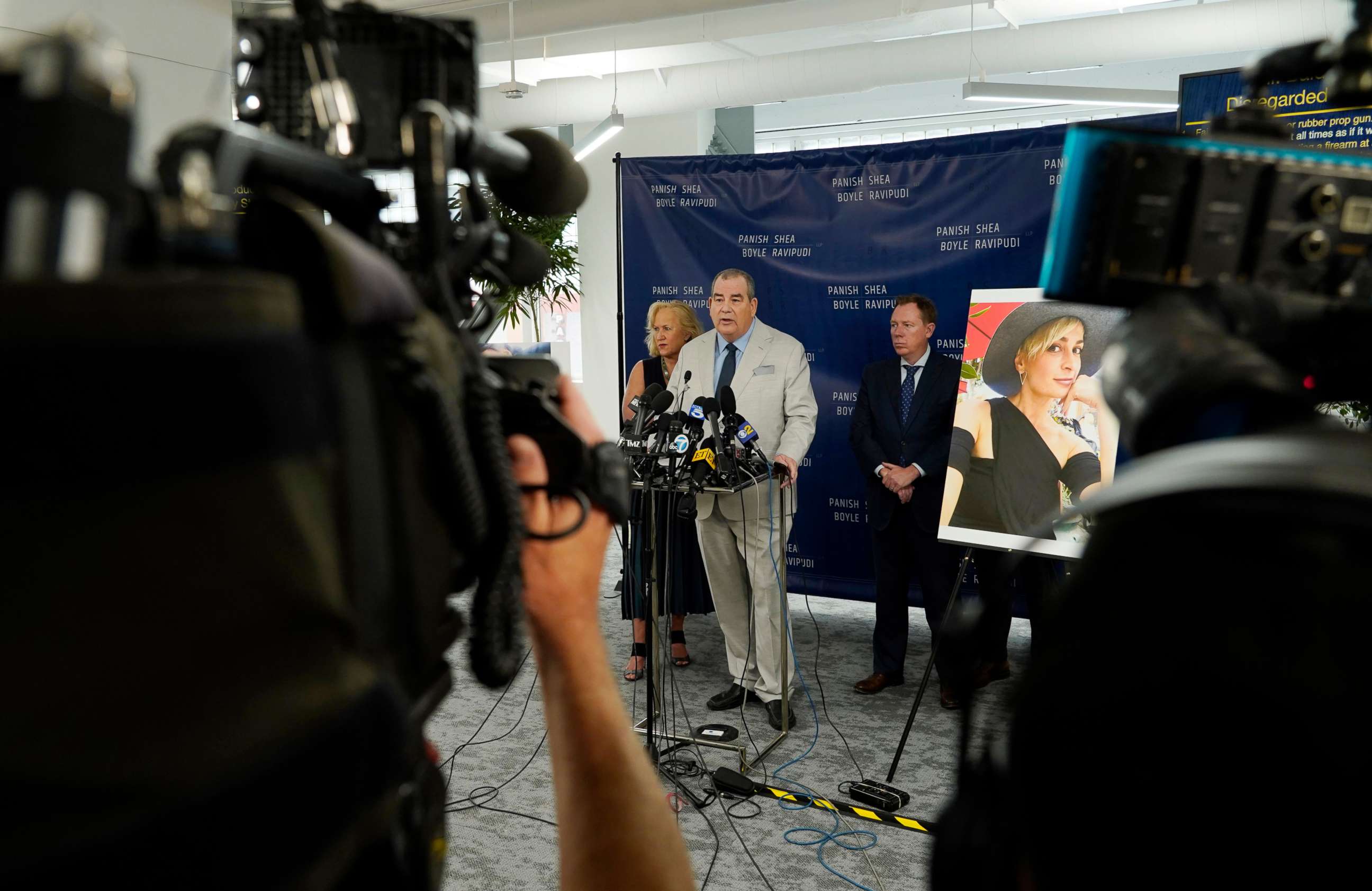 PHOTO: Randi McGinn, from left, Brian Panish and Kevin Boyle, attorneys for the family of cinematographer Halyna Hutchins, stand next to a portrait of Hutchins during a news conference, Feb. 15, 2022, in Los Angeles.