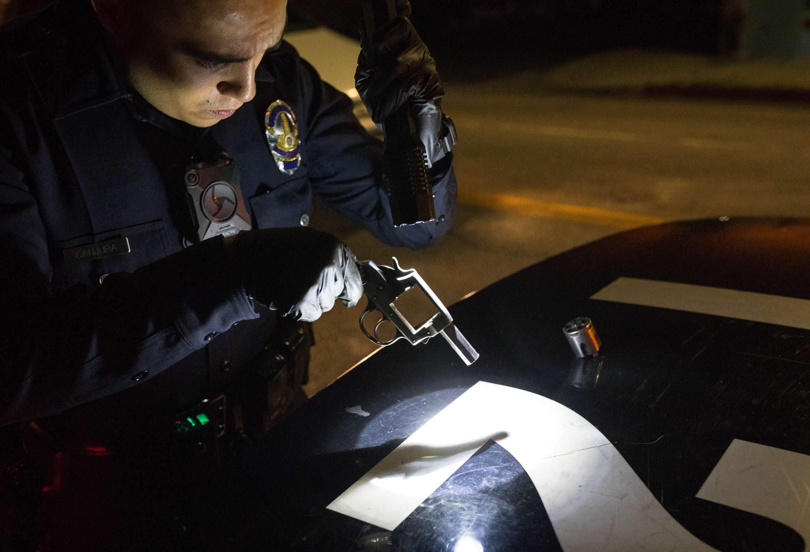 PHOTO: A police officer examines a .38 caliber pistol recovered from a roof after it was thrown by a gang member, May 21, 2017, in Los Angeles.