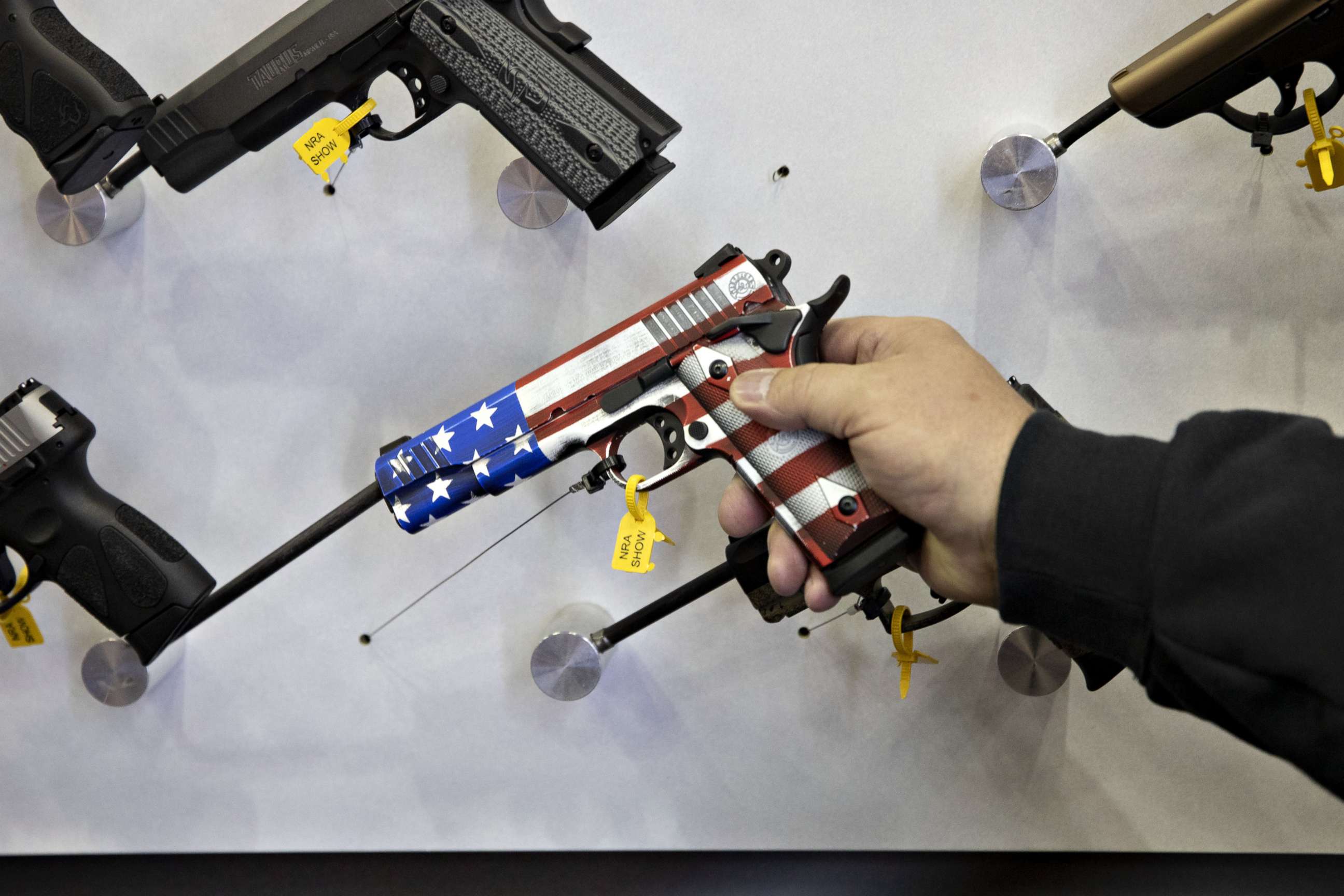 PHOTO: An attendee holds an American flag themed pistol at a vendor's booth during the National Rifle Association annual meeting in Indianapolis, April 27, 2019.