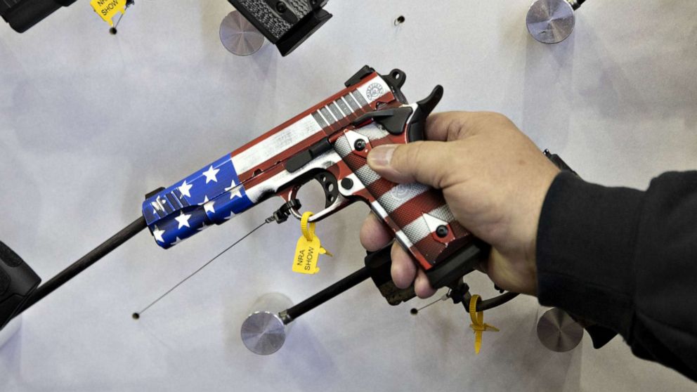 PHOTO: An attendee holds an American flag themed pistol at a vendor's booth during the National Rifle Association annual meeting in Indianapolis, April 27, 2019.