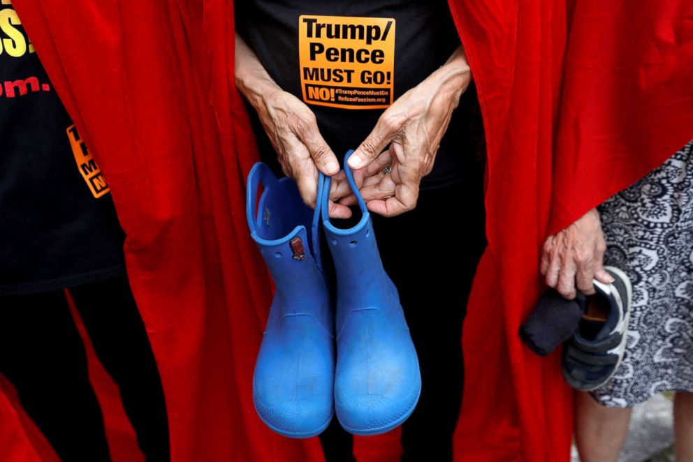 PHOTO: Women dressed in red gowns as worn in the "Handmaids Tale" hold shoes representing immigrant children separated from their parents protest, July 31, 2018, in Manhattan, New York City.