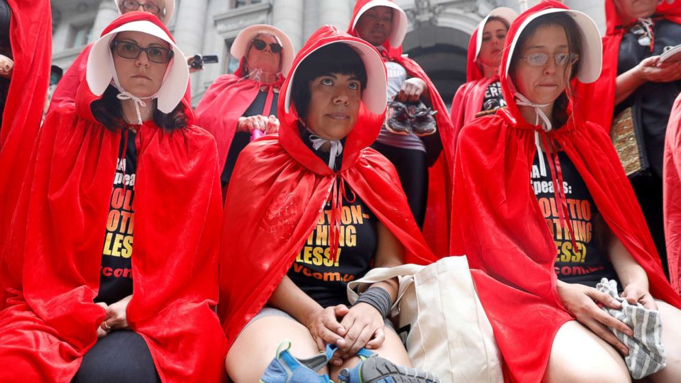 PHOTO: Women dressed in red gowns as worn in the "Handmaids Tale" hold shoes and clothing representing immigrant children separated from their parents as they protest in New York City, July 31, 2018.