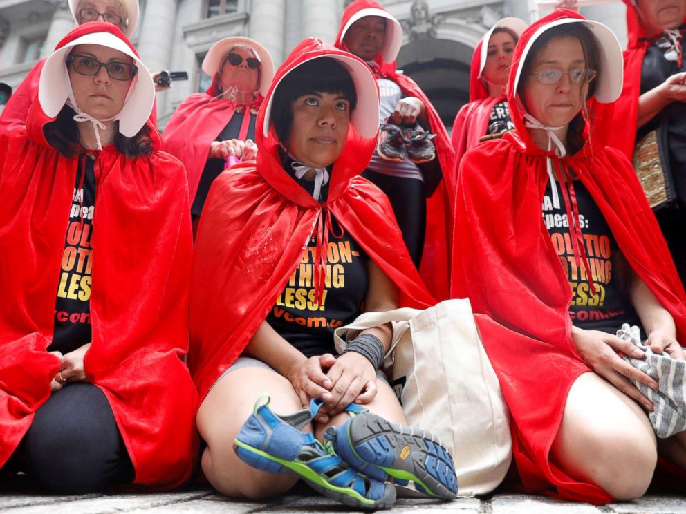 PHOTO: Women dressed in red gowns as worn in the Handmaids Tale hold shoes and clothing representing immigrant children separated from their parents as they protest in New York City, July 31, 2018.