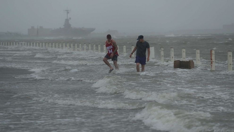 PHOTO: Two men walk on a flooded road as Hurricane Hanna makes landfall, Saturday, July 25, 2020, in Corpus Christi, Texas.