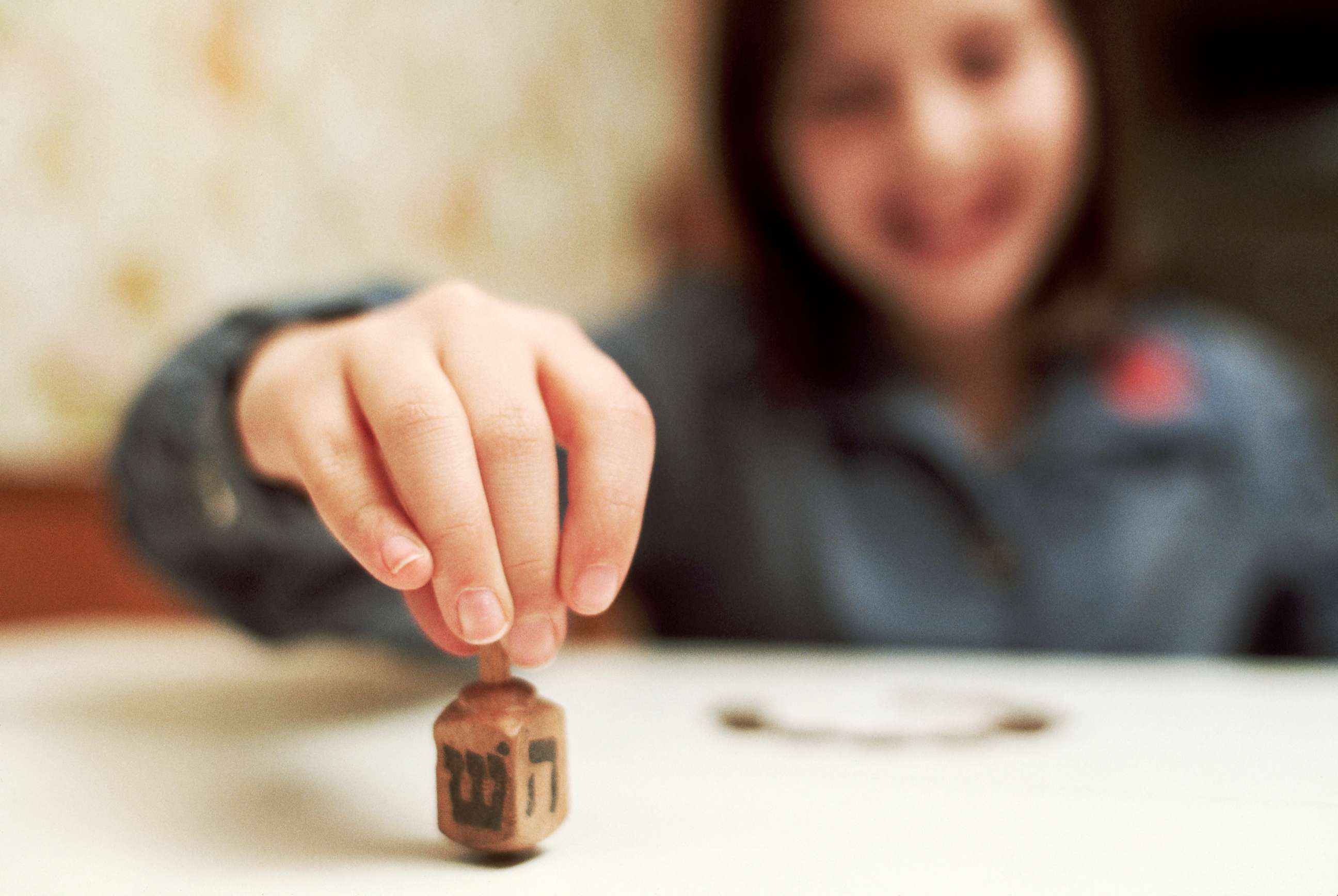 PHOTO: A young girl spins a dreidel.