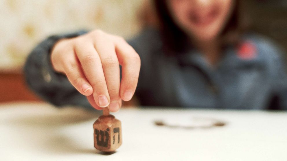 PHOTO: A young girl spins a dreidel.