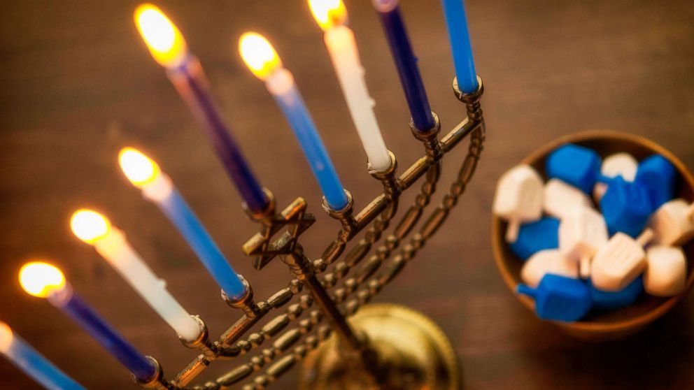 PHOTO: Menorah with burning candles and dreidel.