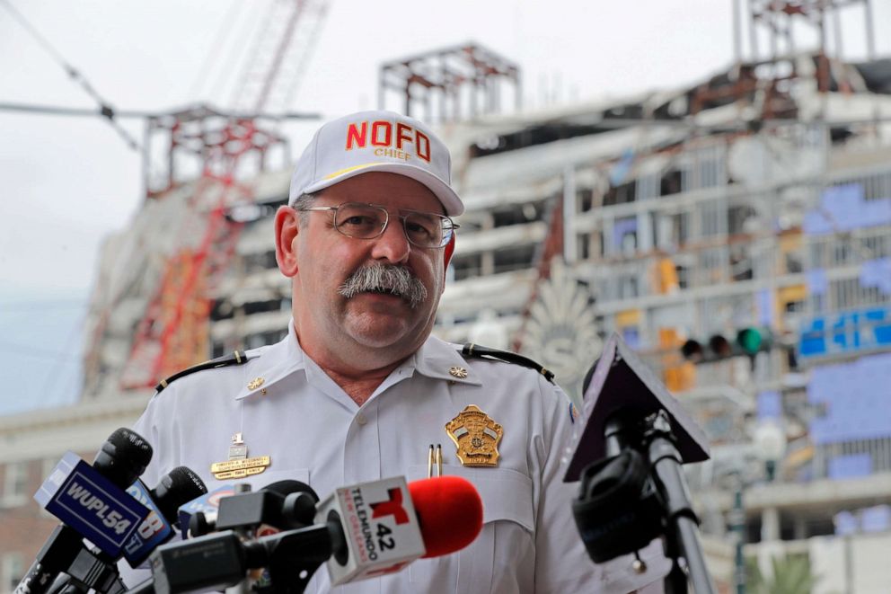 PHOTO: New Orleans Fire Superintendant Fire Superintendent Tim McConnell delivers an update to media for the Hard Rock Hotel building collapse site, seen in the background, in New Orleans, July 20, 2020.
