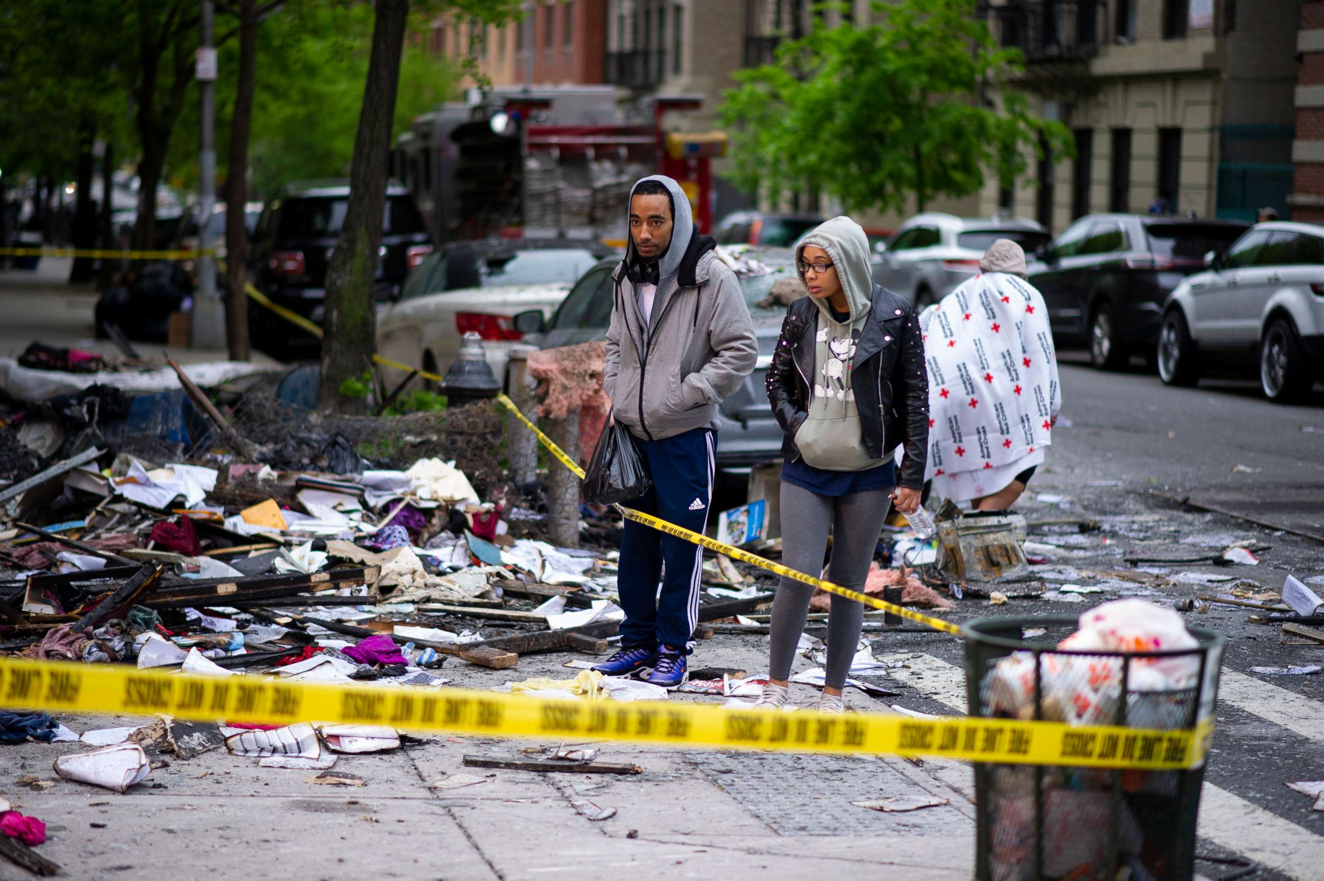PHOTO: People stand near debris after a fatal fire where six people, including four children, died in a city-owned building in the Harlem neighborhood of New York, May 8, 2019.