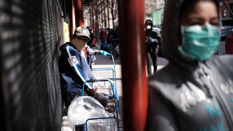 PHOTO: People wait at a food distribution site that has seen a surge in demand due to the coronavirus outbreak, April 7, 2020 in the Harlem neighborhood of the Bronx, in New York City.