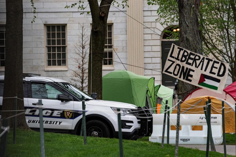 PHOTO: A police cruiser sits by tents and signs that fill Harvard Yard by the John Harvard statue in the Pro-Palestinian encampment at Harvard University in Cambridge, Mass., on May 5, 2024.