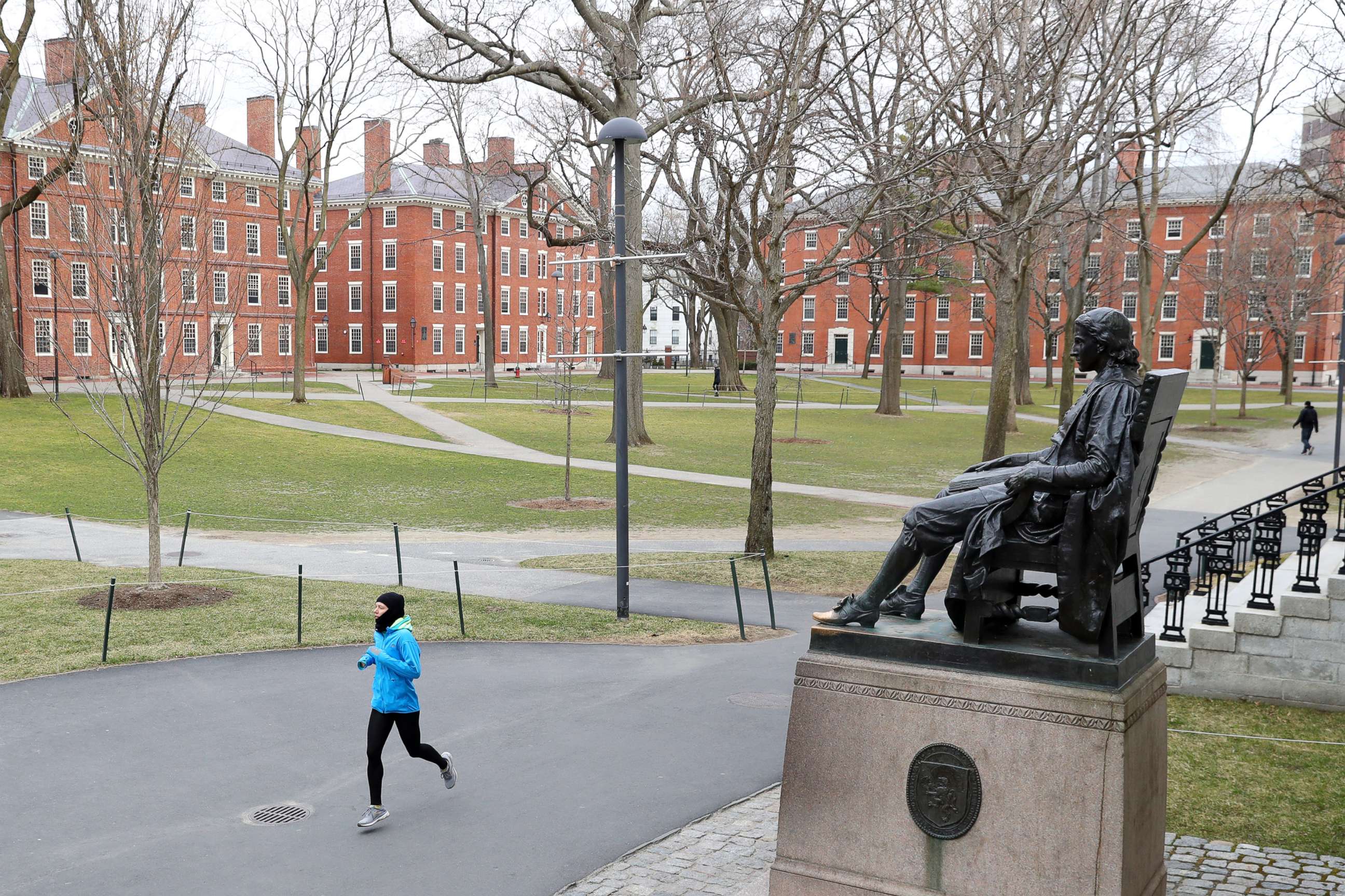 PHOTO: A runner crosses Harvard Yard on March 23, 2020, in Cambridge, Mass. Students were required to be out of their dorms no later than March 15 and finish the rest of the semester online due to the ongoing COVID-19 pandemic..