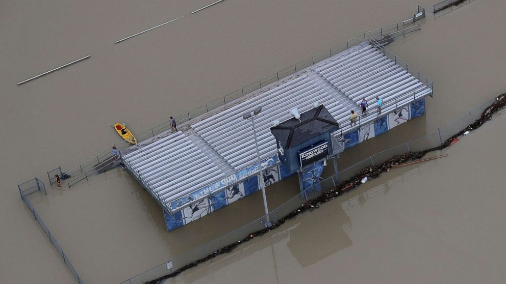 PHOTO: People gather on the bleachers of a flooded high school football field near Lake Houston following Hurricane Harvey, Aug. 29, 2017, in Houston. 