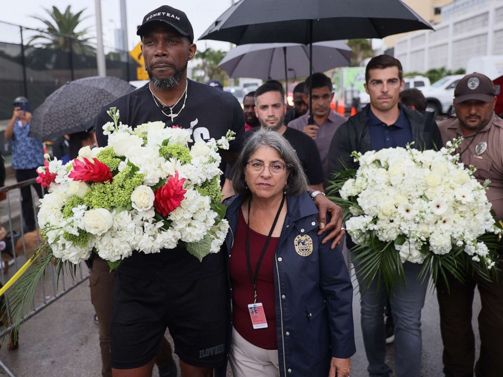 PHOTO: Udonis Haslem, from the Miami Heat basketball team, and Miami-Dade County Mayor Daniella Levine Cava carry flowers to the memorial for those missing from the partially collapsed condo building, June 30, 2021, Surfside, Fla.