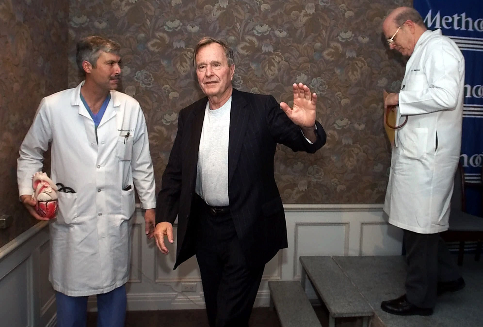 PHOTO: Former President George HW Bush, center, waves as he leaves with cardiologist Mark Hausknecht, left, and Bush's family doctor Ben Orman, right, after a news conference at Methodist Hospital, Feb. 25, 2000, in Houston.