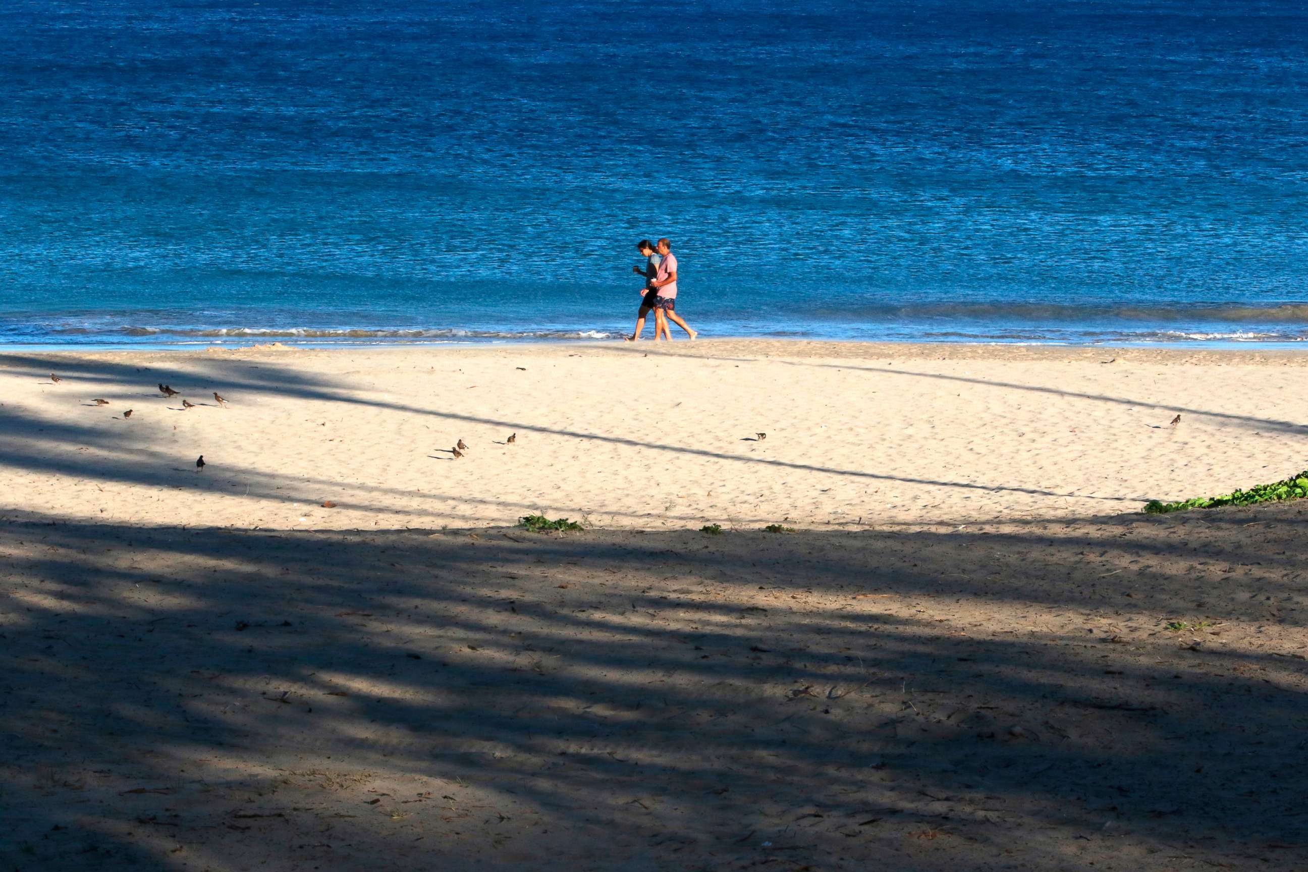 PHOTO: A couple walks on a beach near Waimea, Hawaii, on Friday, Aug. 6, 2021. The area was scorched by the state's largest ever wildfire. 
