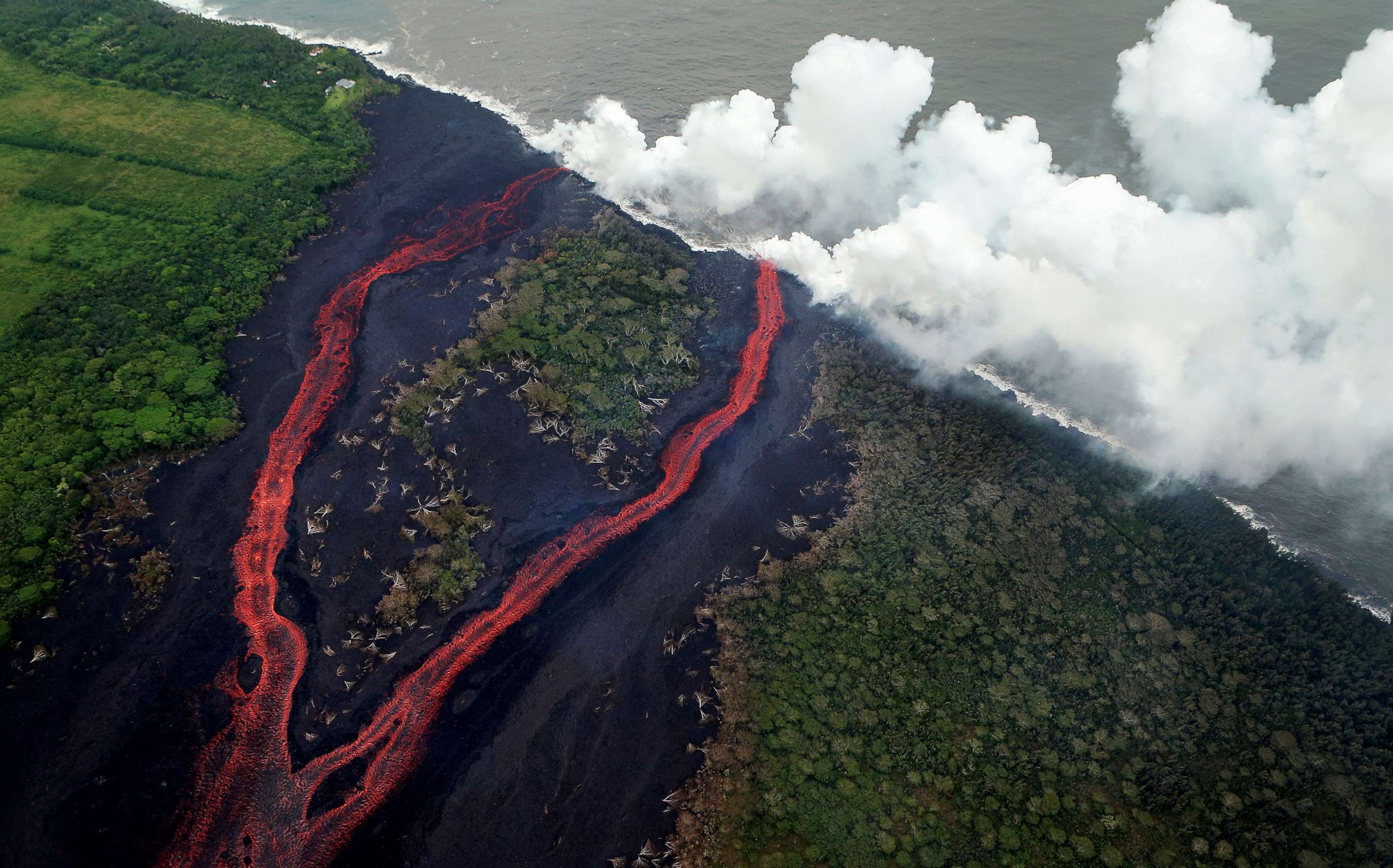 PHOTO: Steam plumes rise as lava enters the Pacific Ocean, after flowing to the water from a Kilauea volcano fissure, on Hawaii's Big Island, May 21, 2018, near Pahoa, Hawaii.