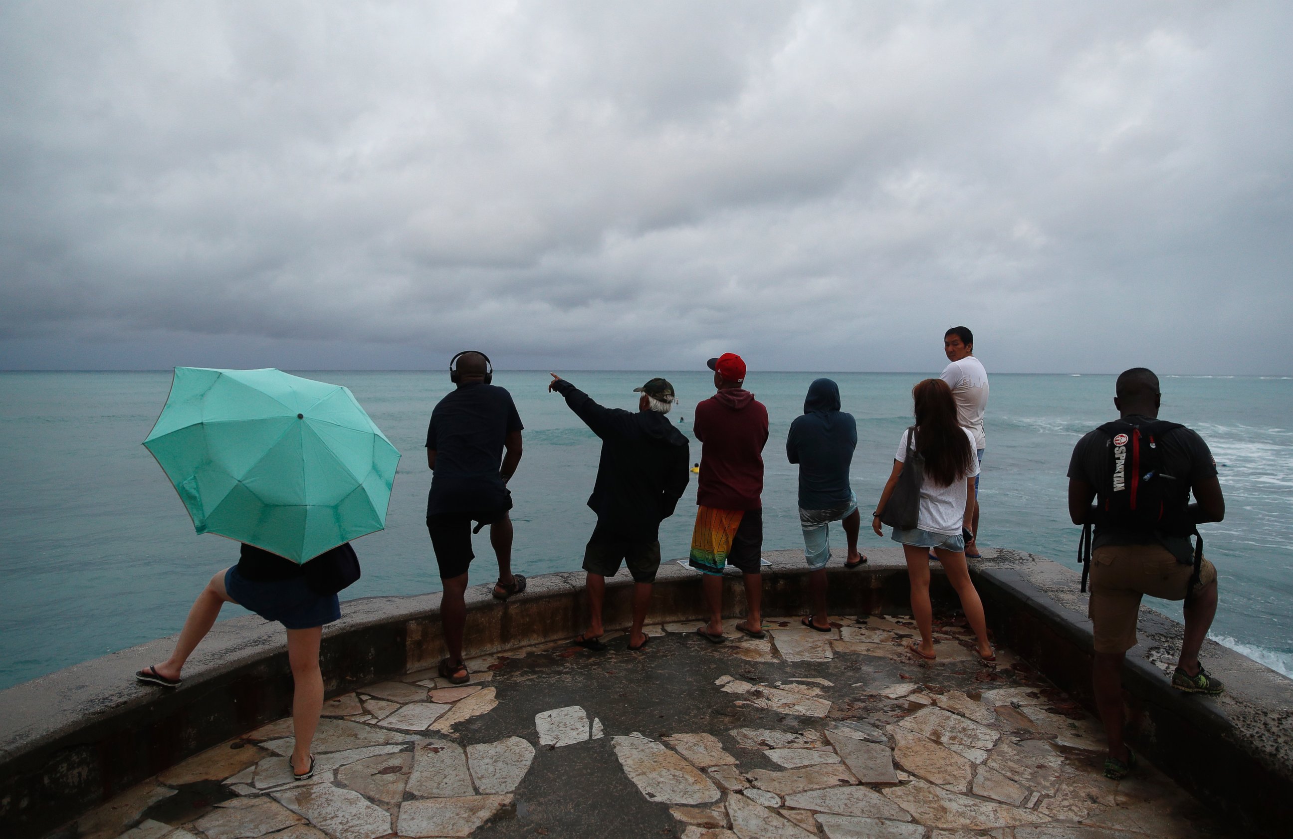 People look out over the ocean along Waikiki Beach in a light rain from Tropical Storm Lane, Saturday, Aug. 25, 2018, in Honolulu..
