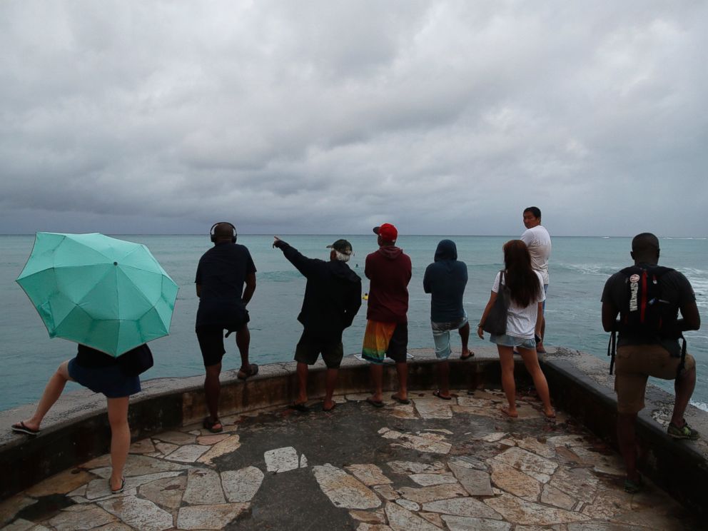 People look out over the ocean along Waikiki Beach in a light rain from Tropical Storm Lane, Saturday, Aug. 25, 2018, in Honolulu..