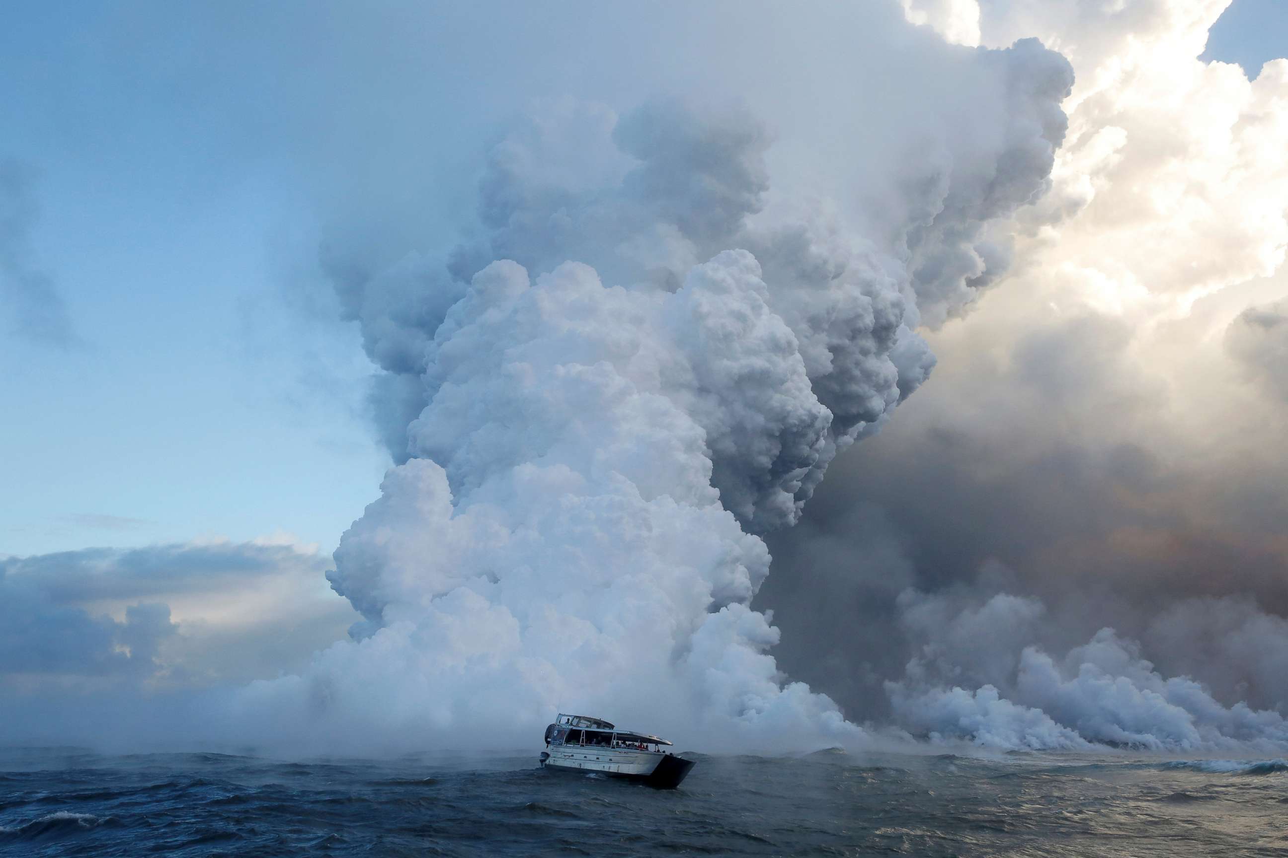 PHOTO: People watch from a tour boat as lava flows into the Pacific Ocean in the Kapoho area, east of Pahoa, during ongoing eruptions of the Kilauea Volcano in Hawaii, June 4, 2018.