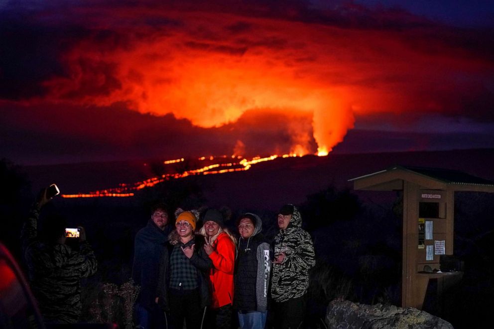 PHOTO: People pose for a photo in front of lava erupting from Hawaii's Mauna Loa volcano, Nov. 30, 2022, near Hilo, Hawaii.