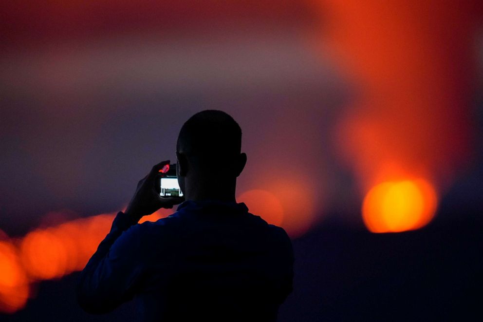 PHOTO: Brian Lichtenstein, takes a photo in front of lava erupting from Hawaii's Mauna Loa volcano, Nov. 30, 2022, near Hilo, Hawaii.