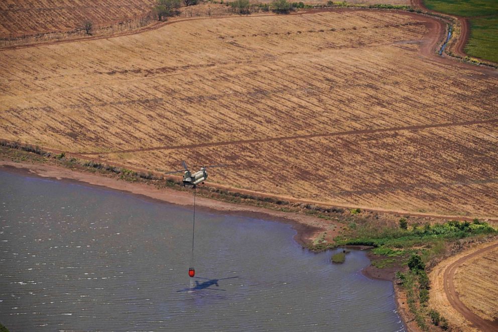 PHOTO: A helicopter with the Hawaii Army National Guard performs aerial water bucket pick up to fight wildfires on the Hawaiian island of Maui, Aug. 9, 2023.