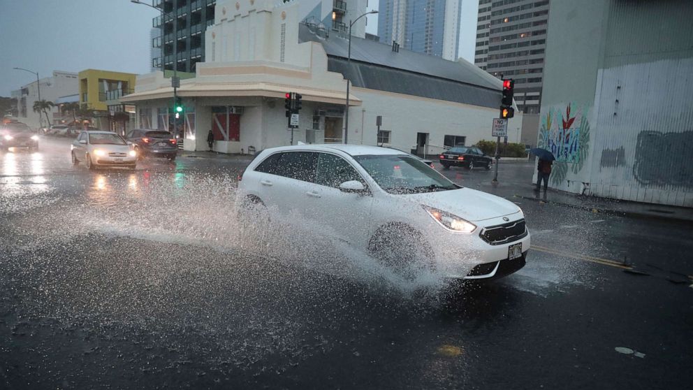 PHOTO: A car turns onto a flooded Cooke Street, Dec. 6, 2021, in Honolulu.