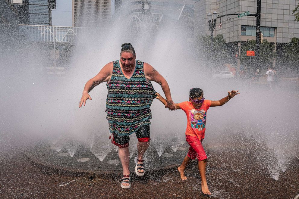 PHOTO: Melissa Green, left, and Amya Wilson, cool off in the Salmon Springs Fountain during an extreme heatwave, Aug. 13, 2021, in Portland, Ore.