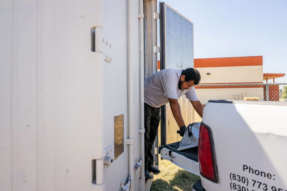 PHOTO: Memorial Funeral Chapel operator Polo Vargas rests while loading a body into a storage freezer, June 28, 2023, in Eagle Pass, Texas.