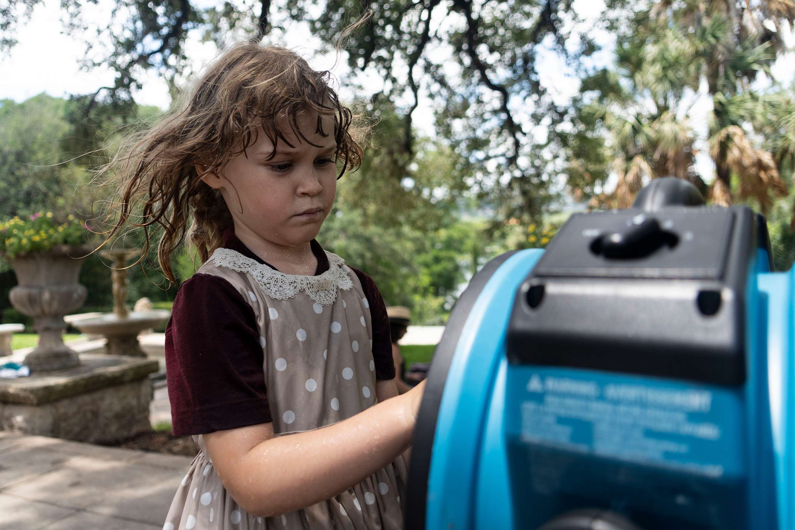 PHOTO: Aventurine Adams checks out a misting fan to cool off from the heat in Austin, Texas, July 8, 2023.