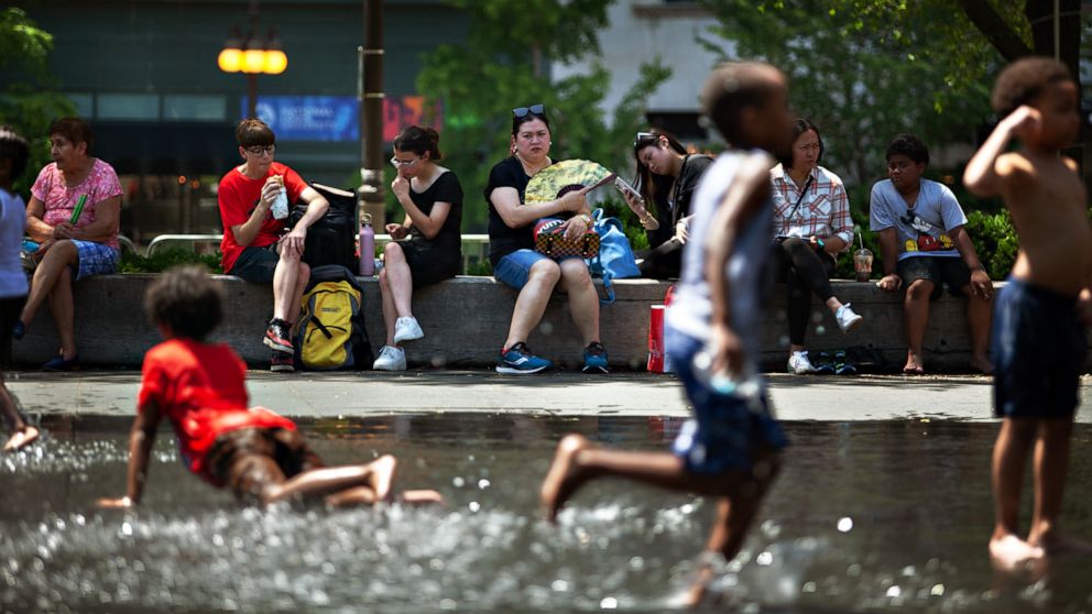 PHOTO: People sit in the shade as children play with water in downtown Chicago on June 14, 2022.