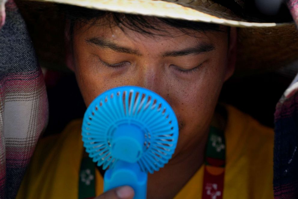 PHOTO: A World Youth Day volunteer uses a small fan to cool off from the intense heat, just outside Lisbon, Portugal, Aug. 6, 2023.