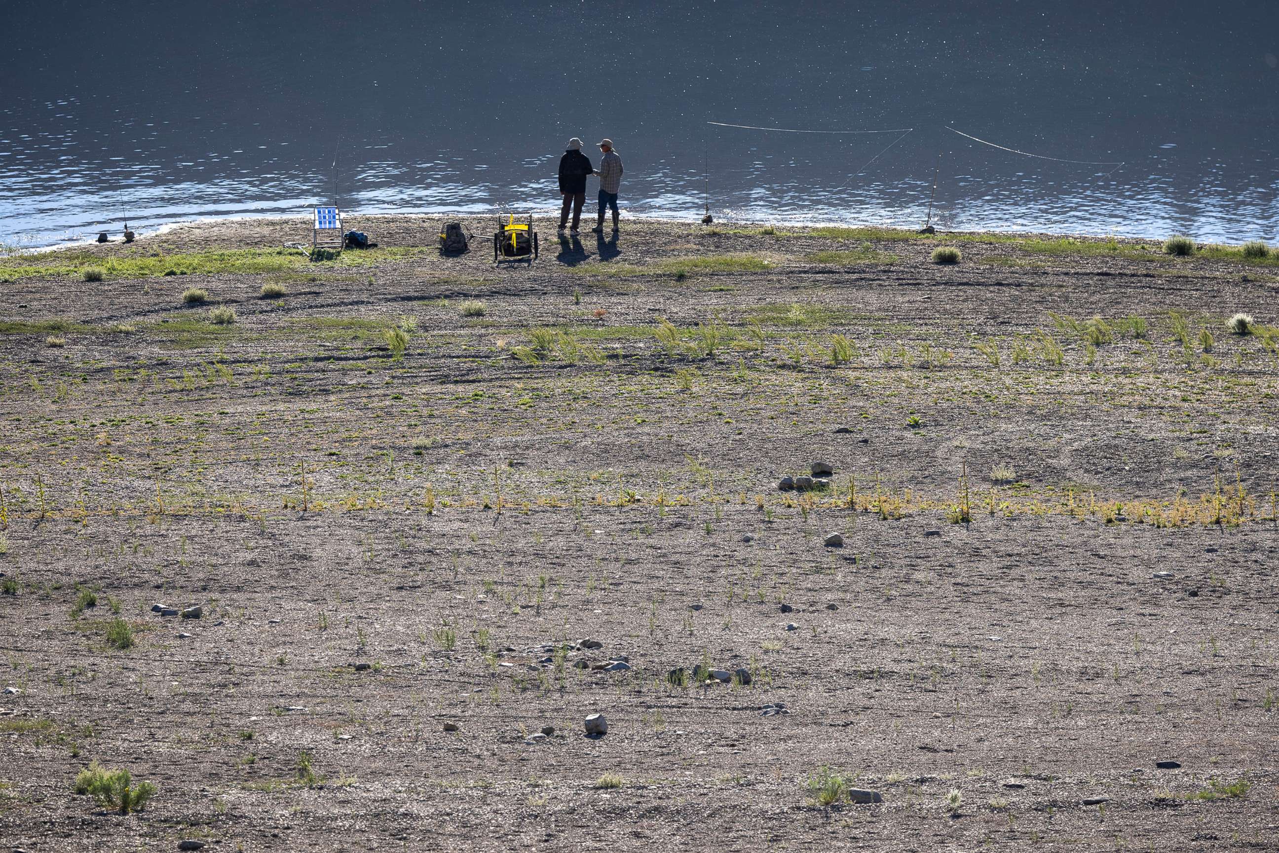 PHOTO: People fish along a shoreline with very a low water level at Grant Lake, which is fed by now-nearly snowless mountains in the Eastern Sierra Nevada, near Lee Vining, Calif., Aug. 11, 2022.