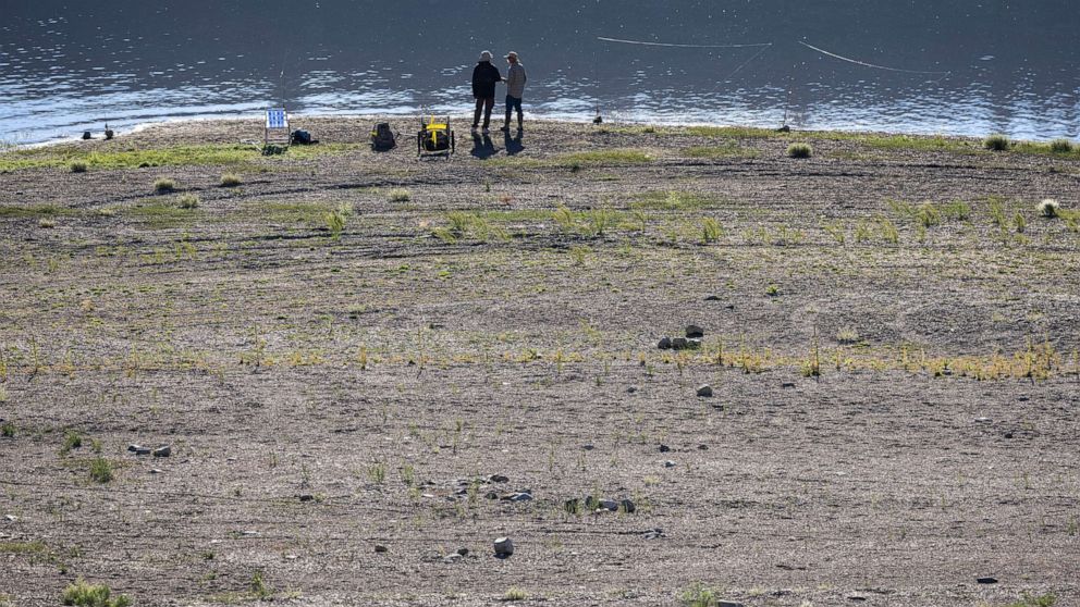 PHOTO: People fish along a shoreline with very a low water level at Grant Lake, which is fed by now-nearly snowless mountains in the Eastern Sierra Nevada, near Lee Vining, Calif., Aug. 11, 2022.