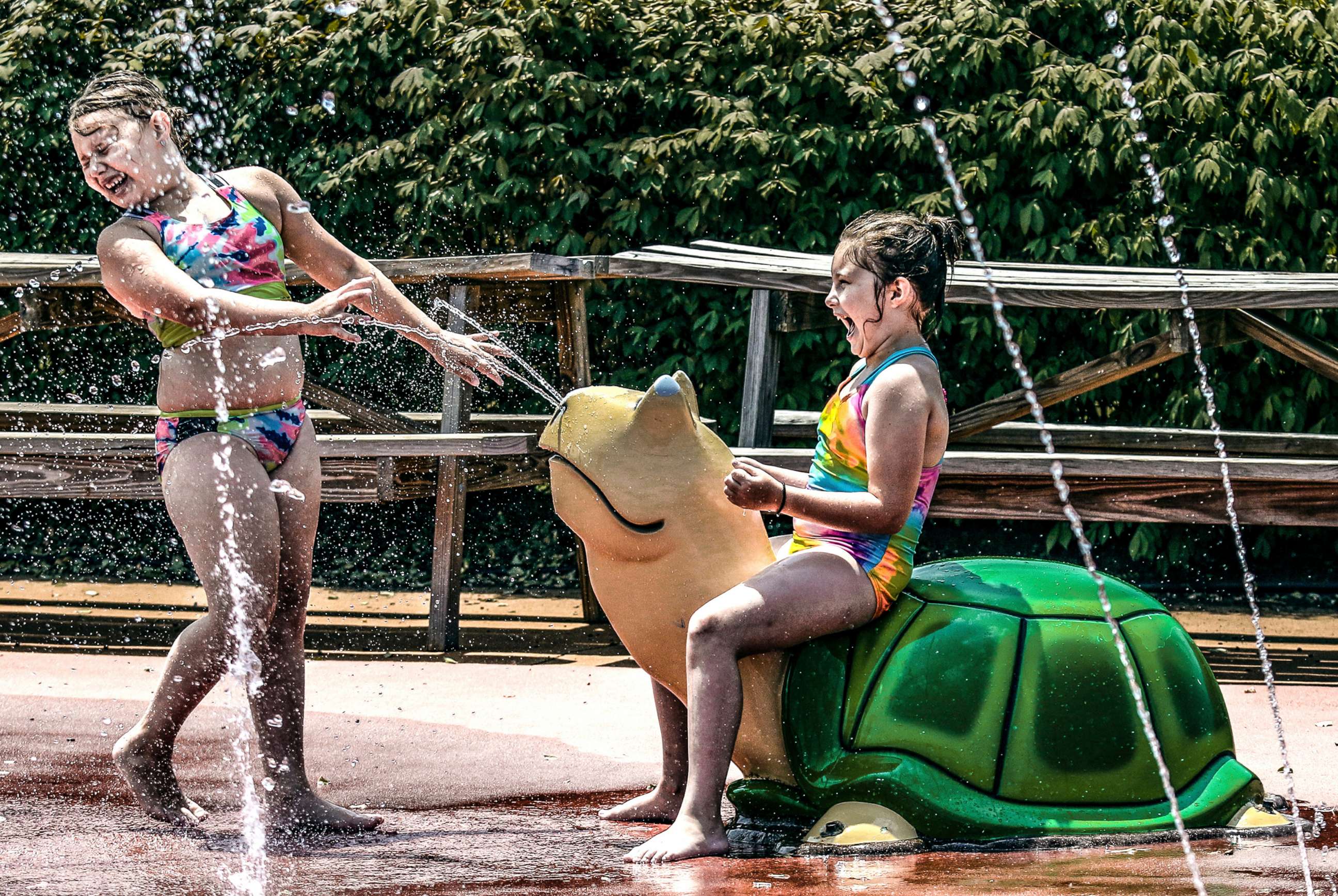 PHOTO: Jemma Velotta, 7, left, and her sister Mya, 8, cool off in the heat at the spray park, July 6, 2022, in Owensboro, Ky.