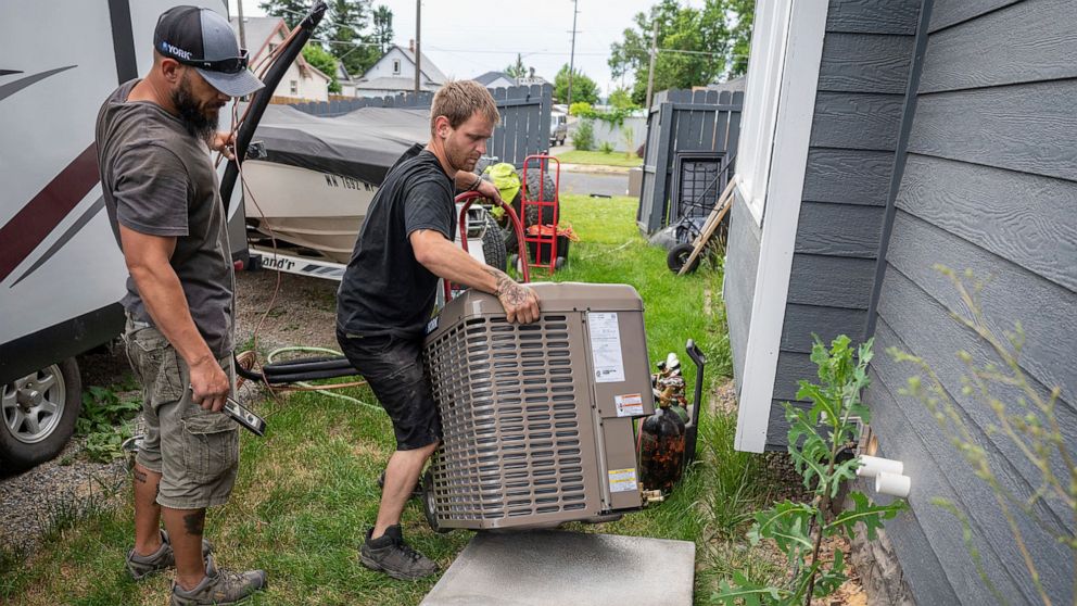 PHOTO: Carl Rocha, left, and Patrick Plummer, with Bills Heating & A/C Install air conditioning and a new furnace at a home on East Wabash Street, June 23, 2021, in Spokane, Wash.