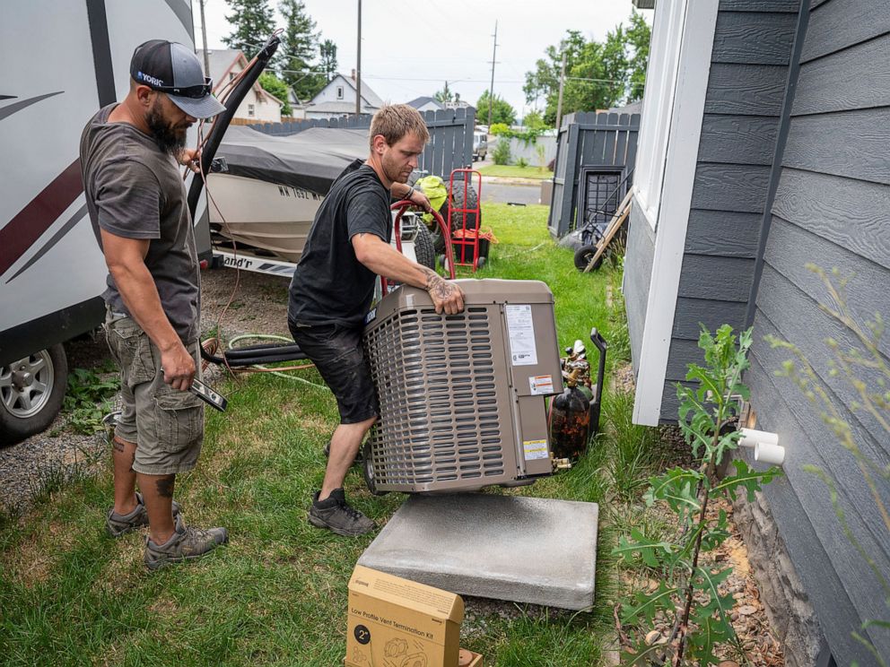 PHOTO: Carl Rocha, left, and Patrick Plummer, with Bills Heating & A/C Install air conditioning and a new furnace at a home on East Wabash Street, June 23, 2021, in Spokane, Wash.
