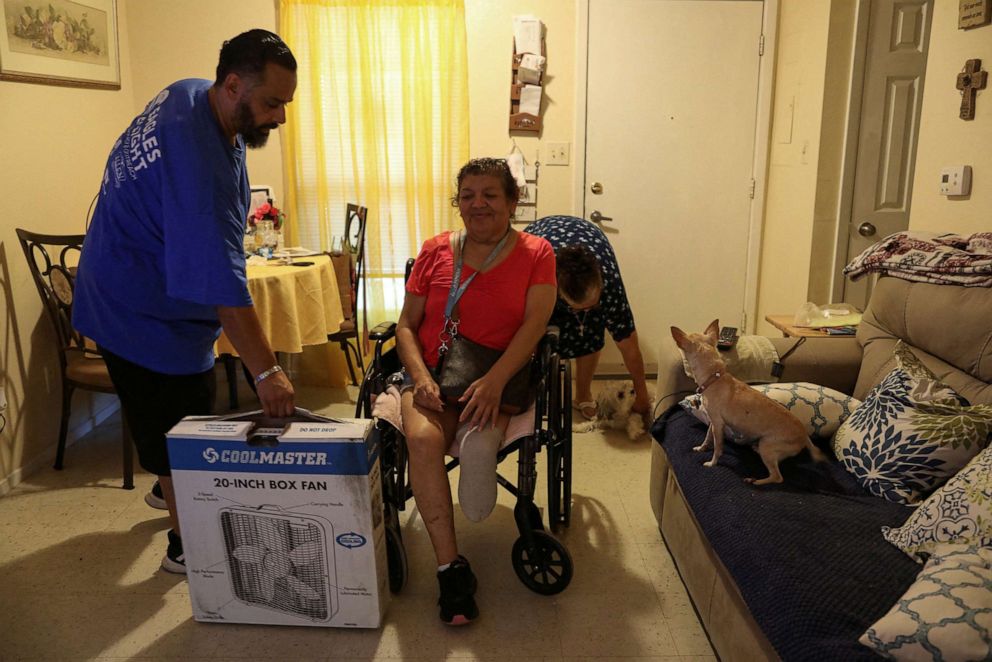 PHOTO: Jon David De Leon, with the non-profit Eagles Flight Advocacy and Outreach, delivers a fan to Juanita Alarcon at Col. George Cisneros Apartments, a senior apartment complex, to help cope with the heat in San Antonio, Texas, July 11, 2022.