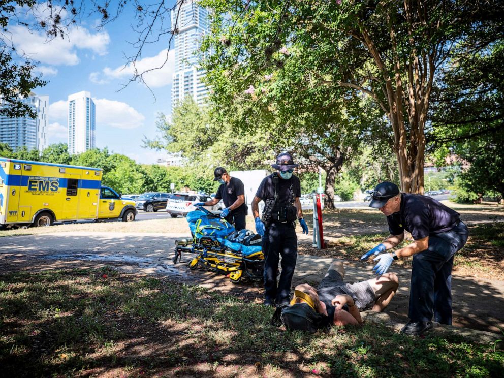 PHOTO: First responders tend to a man in distress who was showing signs of heat exhaustion near Town Lake Trail in Austin, Texas, July 20, 2022.