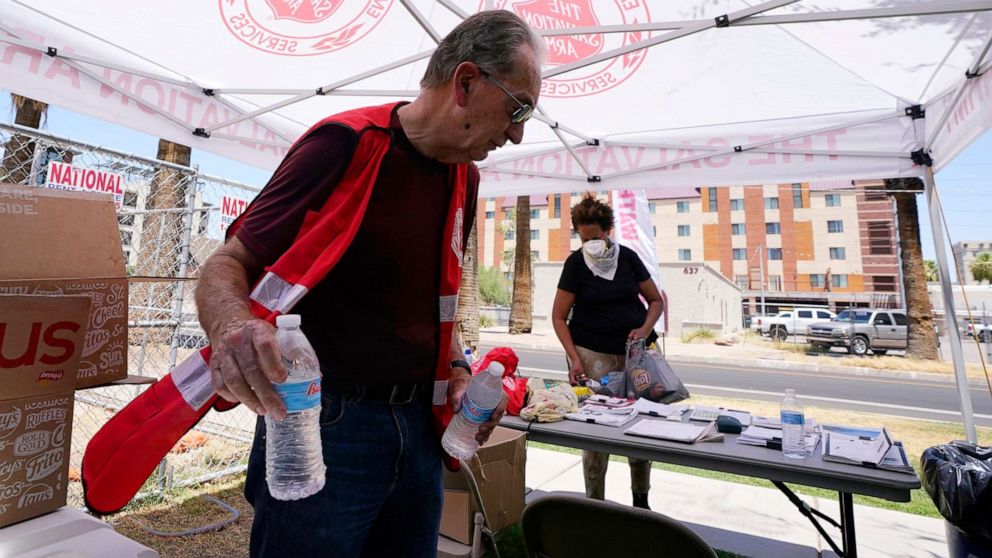 PHOTO: Salvation Army volunteer Cleon Streitmatter hands out water bottles at a Salvation Army heat relief station as temperatures hit 114-degrees, July 11, 2022, in Phoenix.
