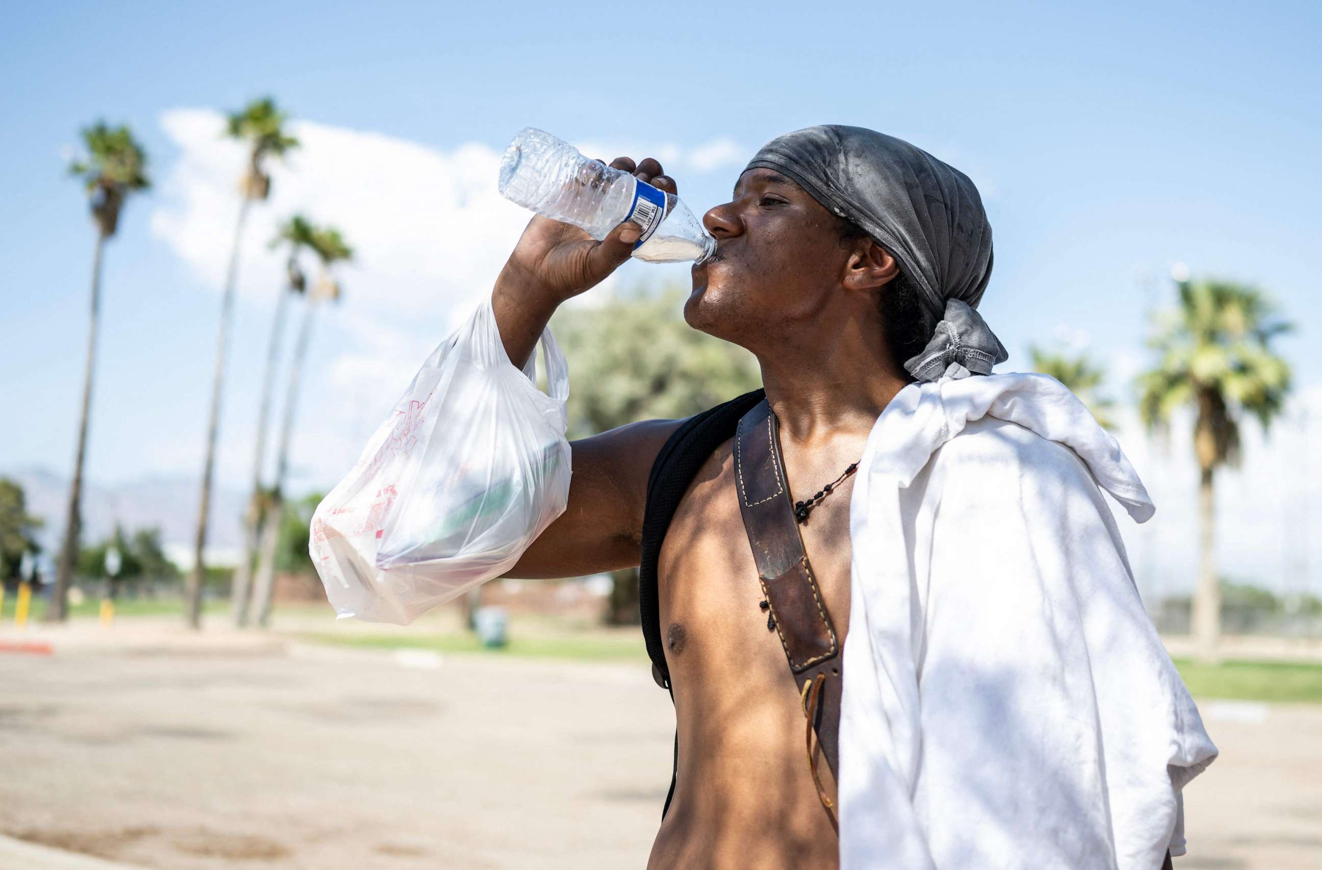 PHOTO: Alonzo McAdams drinks a bottle of water given to him from a Salvation Army truck handing out water, and other supplies for the homeless in Tucson, Ariz., on July 26, 2023.