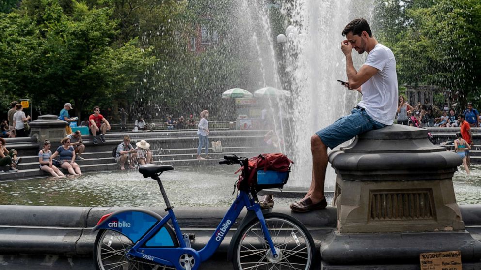 PHOTO: People cool off near the fountain at Washington Square Park during a hot afternoon day on July 17, 2019, in New York.